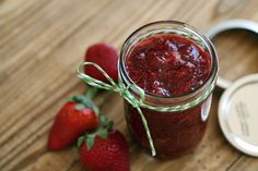 a jar of strawberry jam next to two strawberries