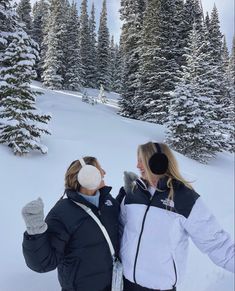 two women are standing in the snow with their arms around each other as they look into the distance