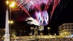 fireworks in the night sky above a crowd of people and statues on a city street