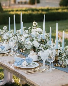 the table is set with white flowers and blue napkins, candles in vases