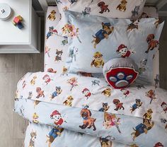 a bed with cartoon characters on it and a toy in the pillow case next to it