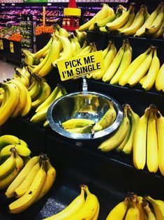 bunches of bananas for sale in a grocery store with a sign saying pick me i'm single