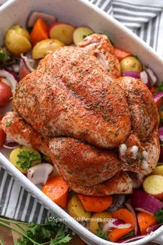 a roasting pan filled with chicken, potatoes and carrots on top of a table