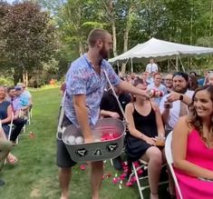 a man holding a bucket full of balls in front of a large group of people