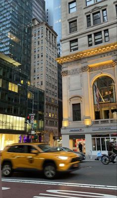 a yellow taxi driving down a street next to tall buildings