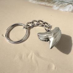 a shark tooth shaped keychain on the beach