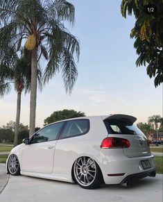 a white car parked in front of some palm trees