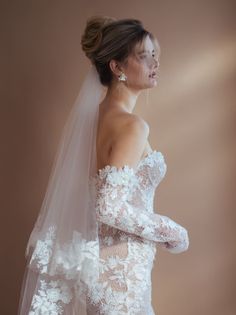 a woman in a wedding dress with a veil on her head and hands behind her back