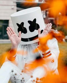 a person sitting on the ground wearing a white hat with black eyes and hands in front of their face