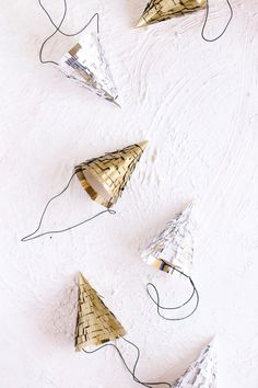 four gold and white paper cones with wires attached to them on a white surface,