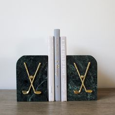 two bookends made out of marble with gold golf clubs and tees on them