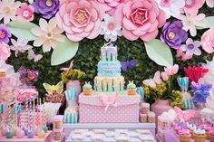 a table topped with lots of cake and cupcakes covered in paper flower decorations