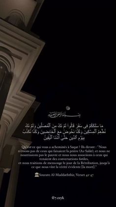 an arabic text on the side of a building at night with a clock tower in the background