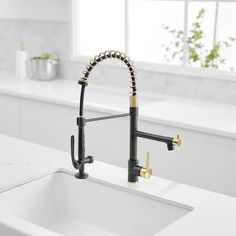 a white kitchen sink with black faucet and gold handles