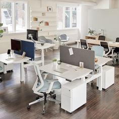 an office with desks, chairs and computer screens on the tables in front of them