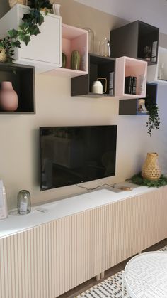 a flat screen tv mounted to the side of a wall next to a white table