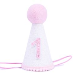 a pink and white birthday hat with a number one on it