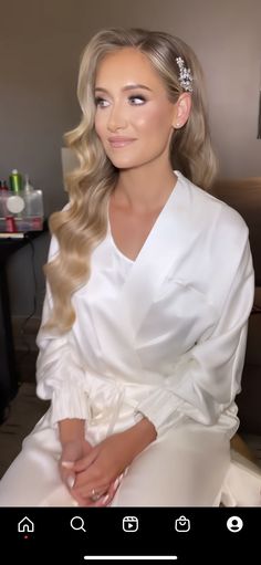 a woman with long blonde hair sitting on a couch wearing a white dress and holding her hands in her pockets