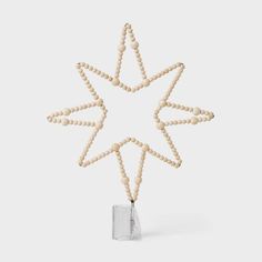 a wooden beaded star ornament hanging from a string on a white background