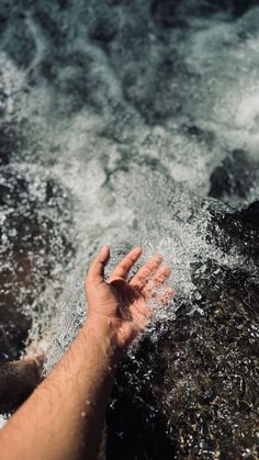 a hand reaching out for something in the water that is splashing on it's side