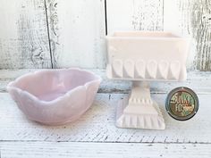 a pink bowl and brush on a white wooden surface