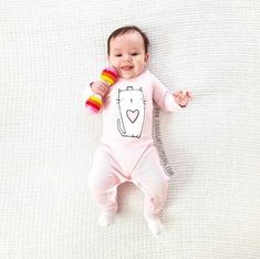 a baby laying on top of a white blanket holding a toy in it's hand