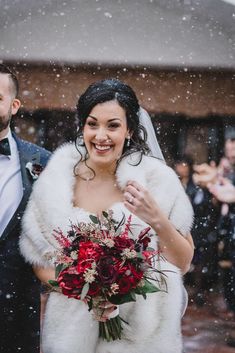 a bride and groom walking through the snow