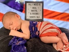 a baby sleeping on top of a blanket next to an american flag