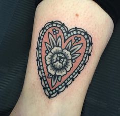 a heart shaped tattoo with a flower on the inside of it's center piece