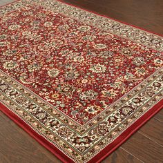 a large red rug on the floor in a room with hardwood floors and wooden floors