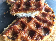 two waffles with cream on them are sitting on a black surface and one is cut in half