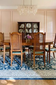 a dinning room table with chairs and china cabinet in the back wall behind it