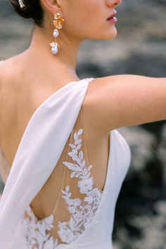 the back of a woman's dress with white flowers and leaves on her shoulder