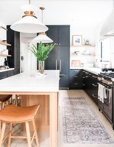 a kitchen with black cabinets, white counter tops and an area rug on the floor