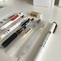 several pens sitting on top of a table next to an eraser and pencil holder