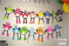 a bulletin board with colorful paper cutouts hanging from it's sides and on the wall