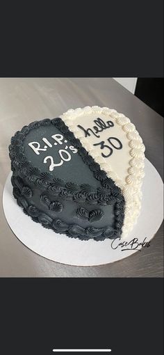 a heart shaped cake with black and white frosting on the top is sitting on a table