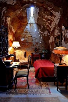 a bedroom with a bed, desk and chair in it's cave like setting