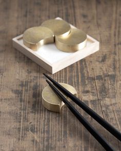 chopsticks and some gold discs on a wooden table