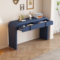 a blue console table with two drawers on each side and a shelf below it for books