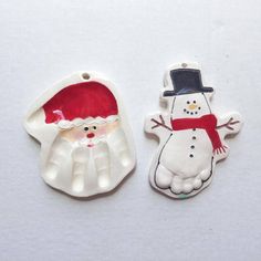 two ceramic christmas ornaments on a white surface