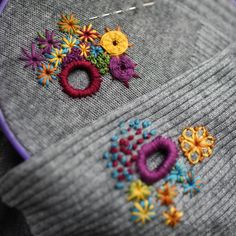 a close up view of some embroidery on a piece of fabric with flowers and rings