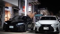 two black and white cars parked on the side of a street next to each other