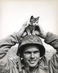 a man wearing a helmet holding a kitten on his head