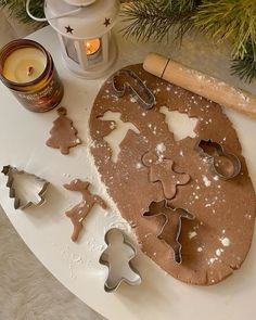 cookie cutters and cookies on a table next to a christmas ornament with candles