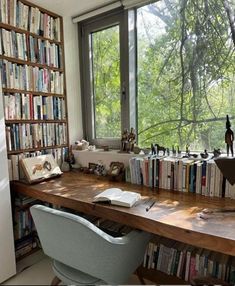 a desk with many books on it in front of a window filled with lots of books