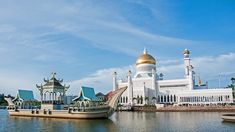 a large white building sitting on top of a lake next to a tall golden dome