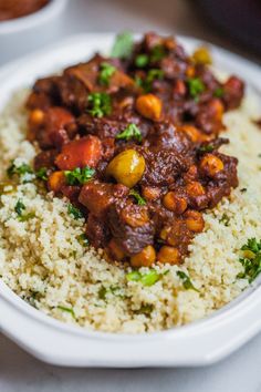 a white bowl filled with rice covered in meat and veggies on top of it