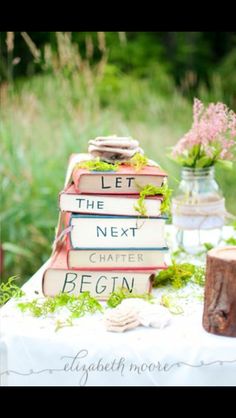 a stack of books sitting on top of a white table covered in grass and flowers