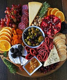 a platter filled with cheese, crackers, olives, fruit and nuts